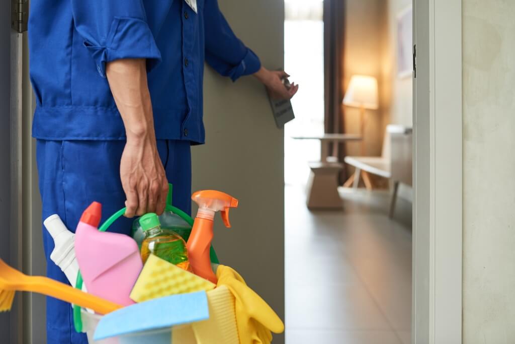 cleaner-walking-into-hotel-room-with-tools-detergents